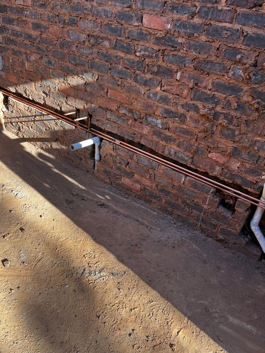 Copper supply line and waste stub run along a brick wall