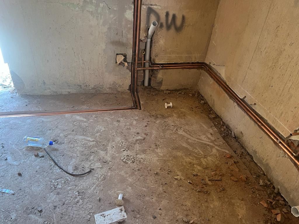 Copper pipework run along the base of a room during renovation