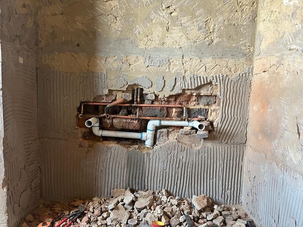 Concealed copper and PVC pipework set into a wall before tiling