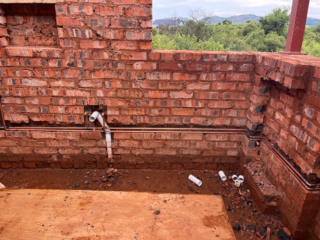 Copper and PVC pipework installed in a partly built brick structure