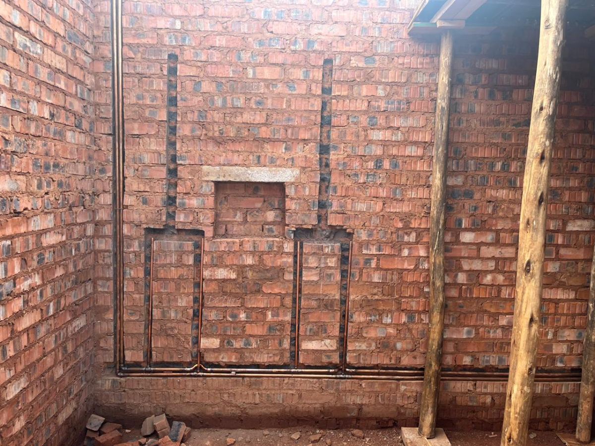 Chased copper risers set into a brick wall for wall-mounted fittings