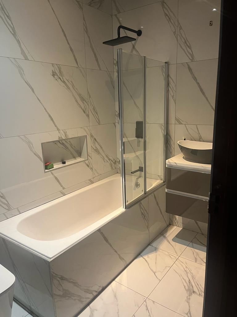 Completed marble-tiled bathroom with built-in bath, rain shower and vessel basin