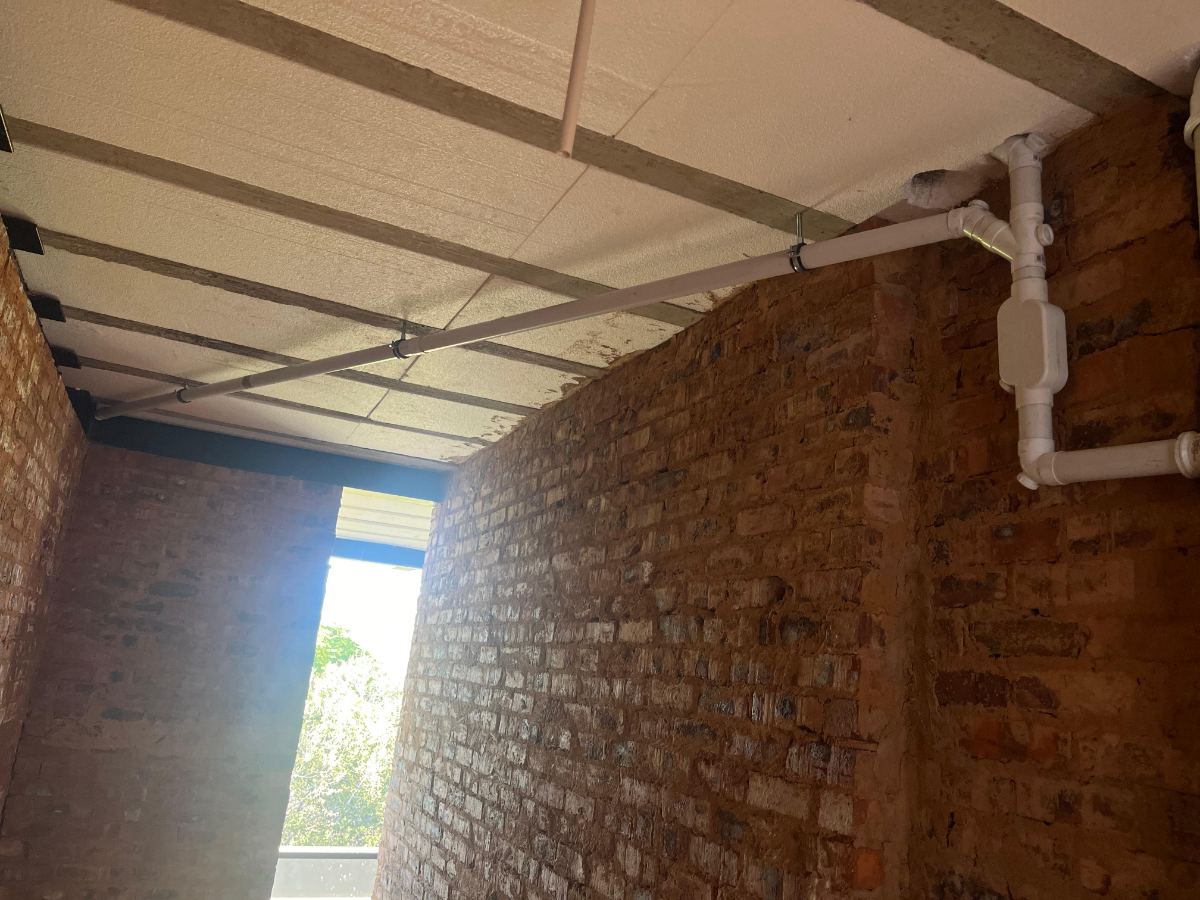 Overhead PVC waste pipework fixed to a ceiling on a new build