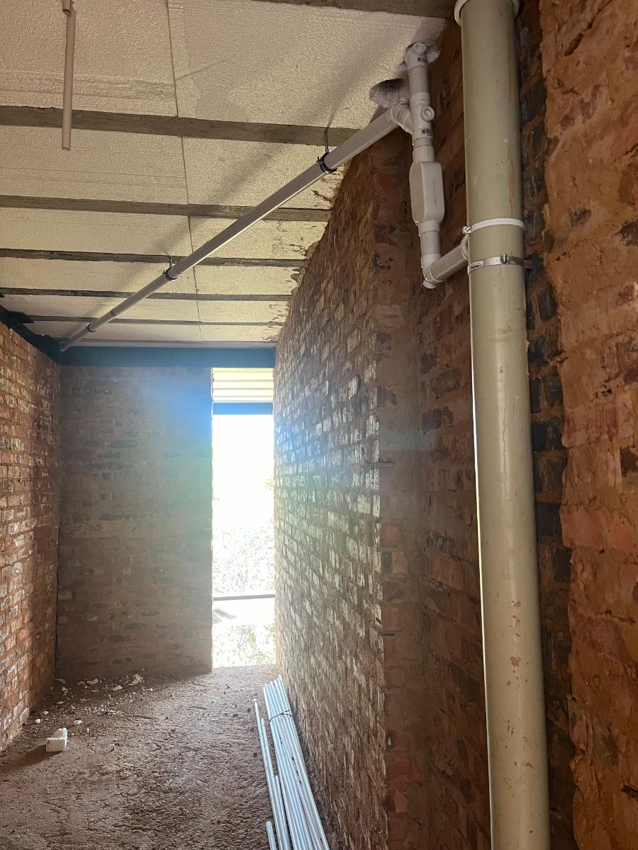 PVC soil and waste pipes routed along a brick wall and ceiling