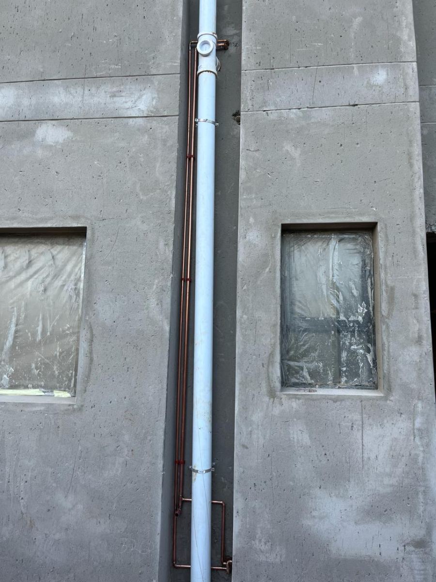 External soil stack and copper supply lines fixed to a building facade