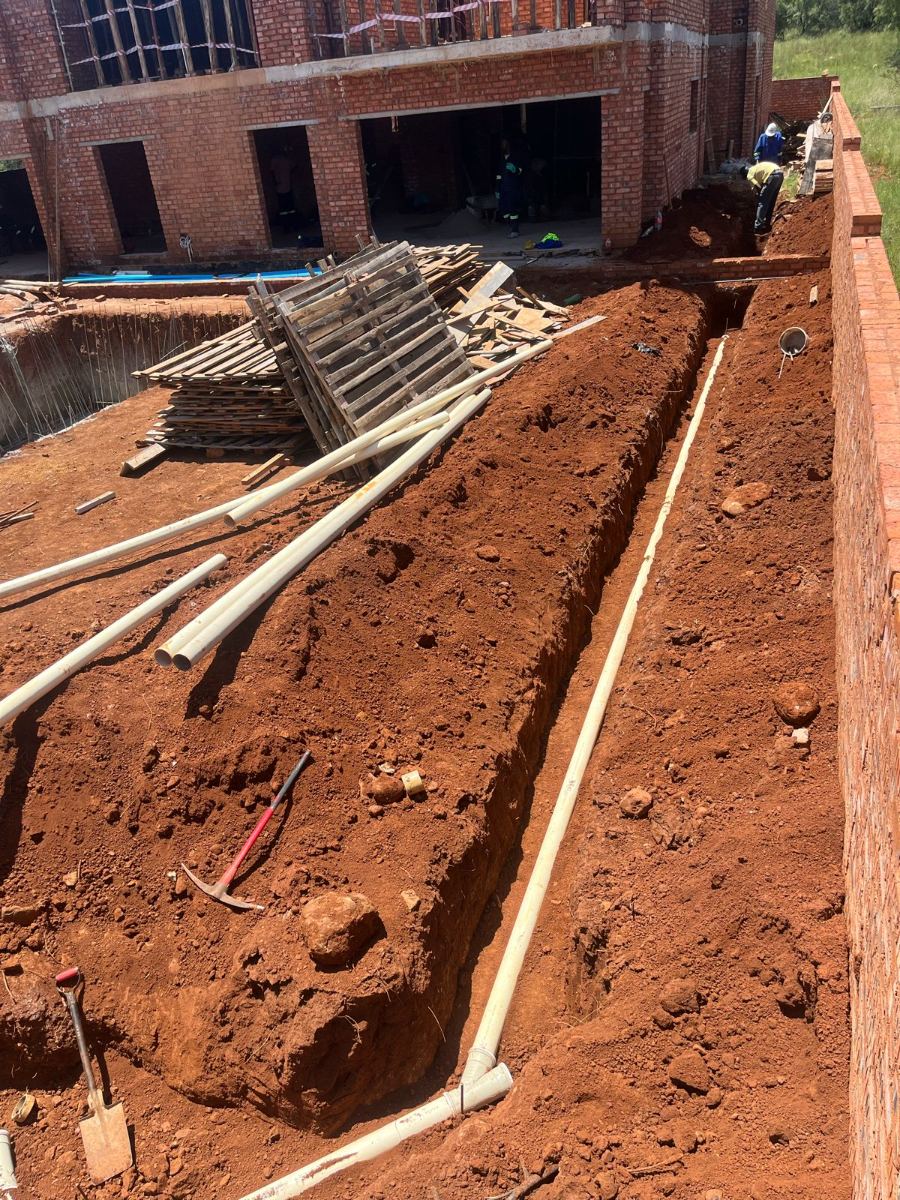 Excavated trench with PVC drainage pipework on a construction site